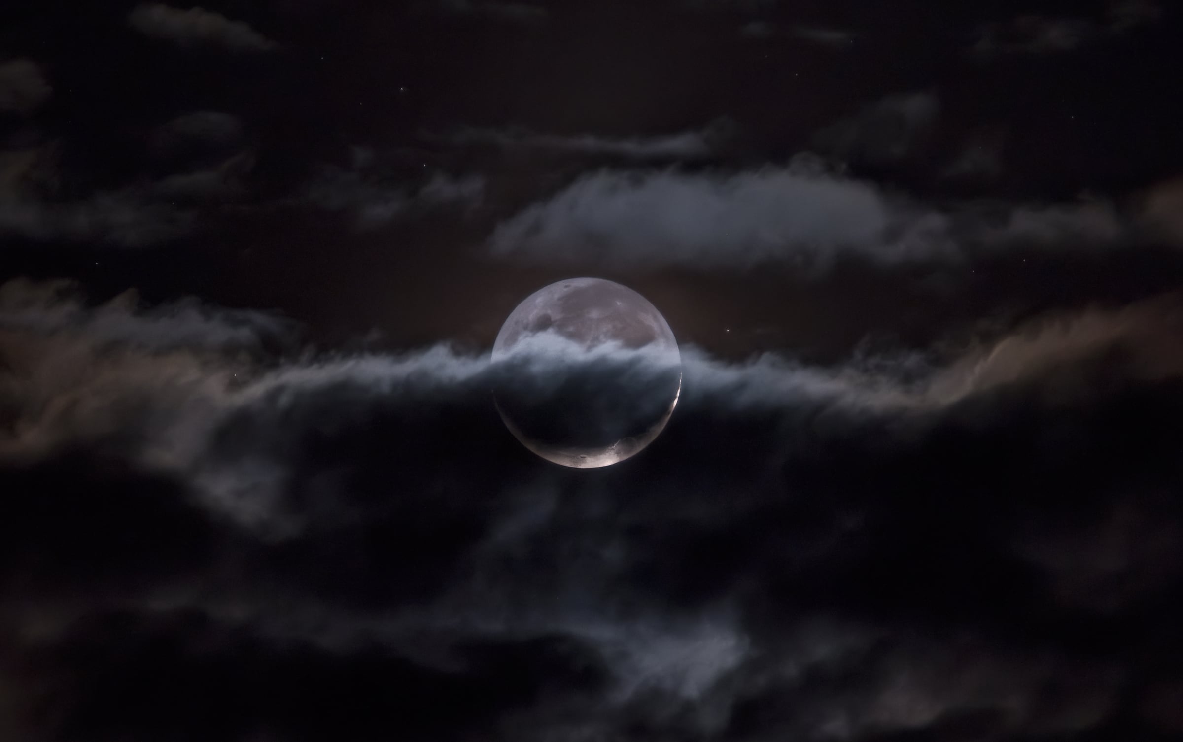 Luna con luz cenicienta entre nubes
