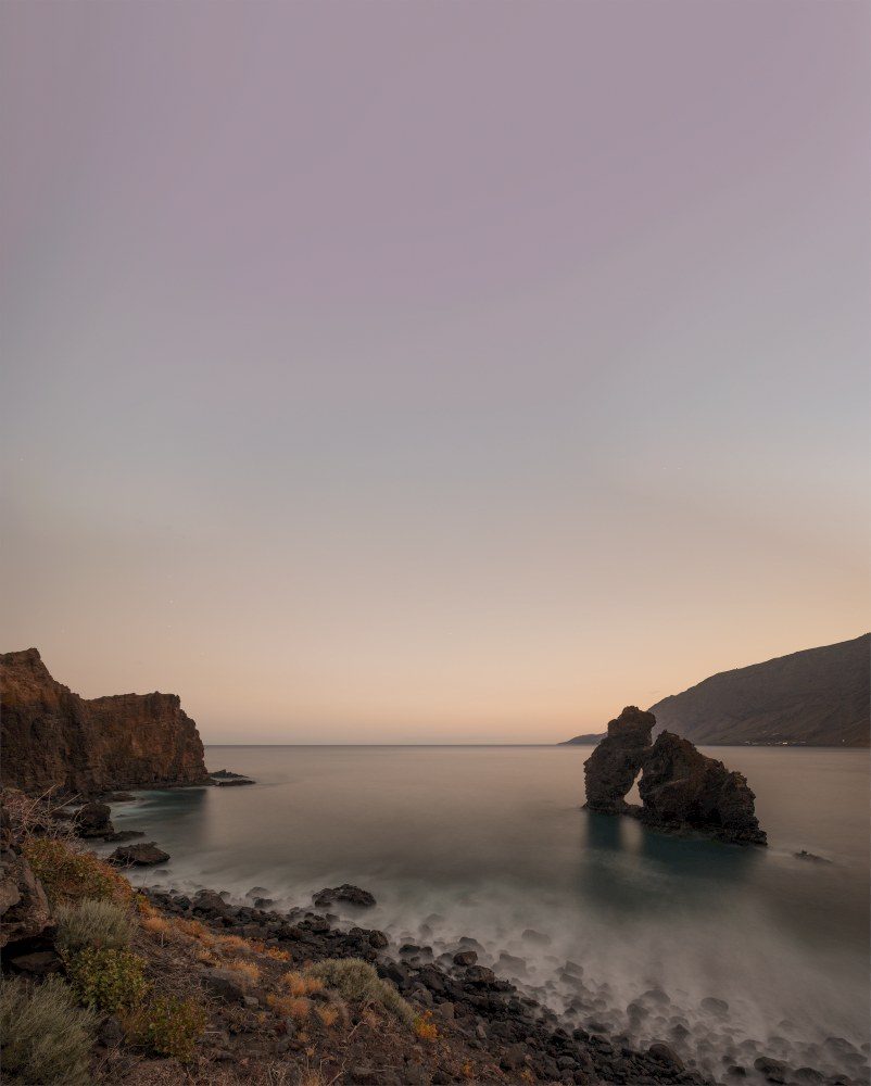 El Roque de la Bonanza, en El Hierro, captado en la hora azul con el mar en larga exposición, antes de unir el cielo nocturno